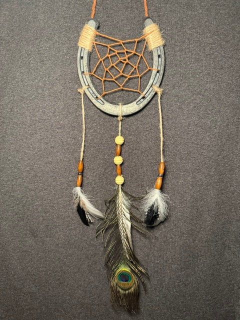 Handmade horseshoe dreamcatcher with orange web, wood beads and peacock feather