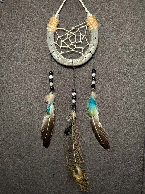 Handmade horseshoe dreamcatcher with white web, turquoise accents and peacock feather